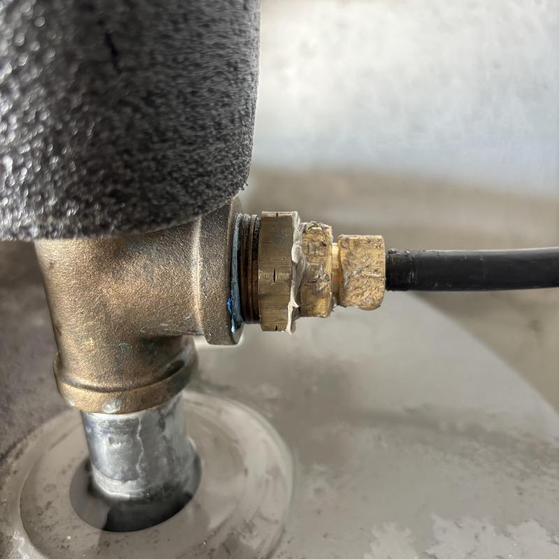 Brass water heater fitting with attached hose connection