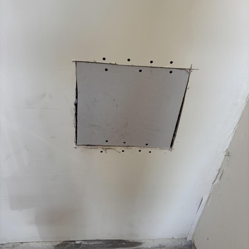 Drywall patch with screw holes in white wall