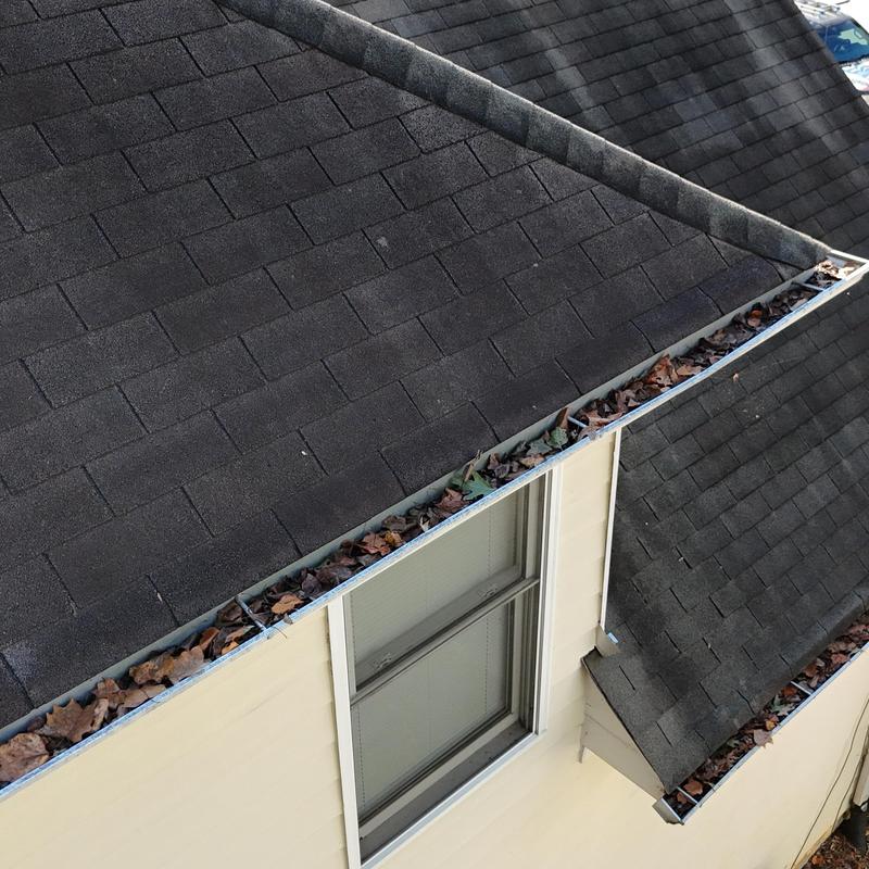 Gutters filled with dry leaves along asphalt shingle roof