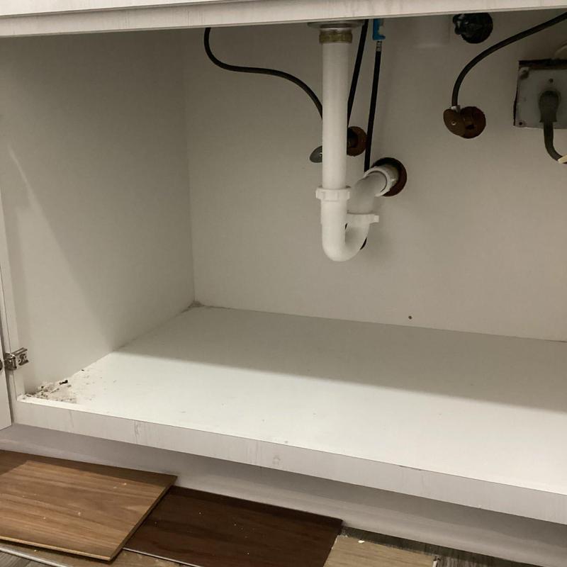 Kitchen sink drain pipes under cabinet with countertop panels