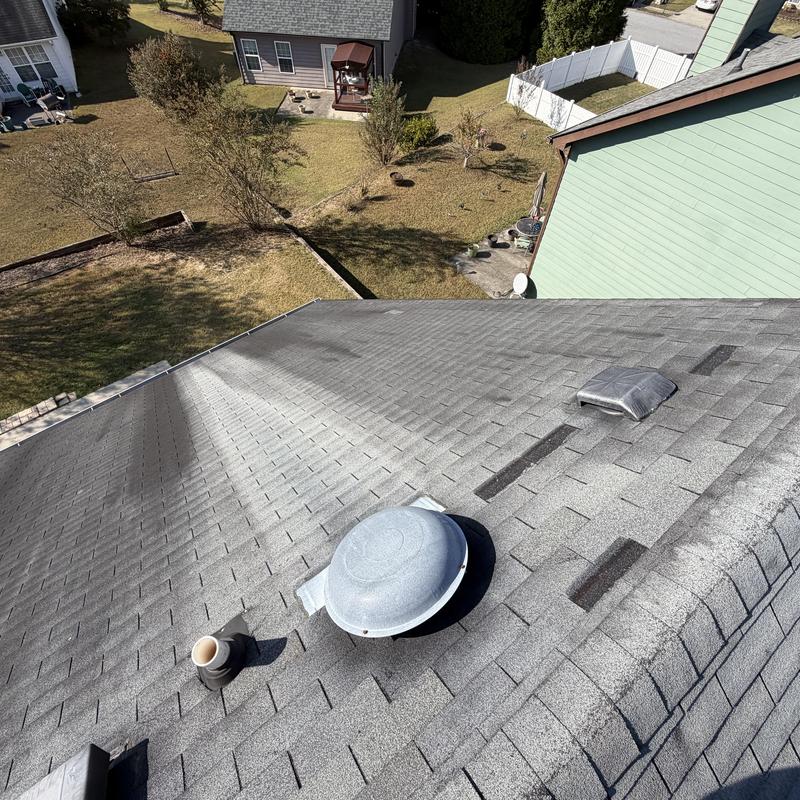 Asphalt roof shingles with ventilation pipes and missing shingles
