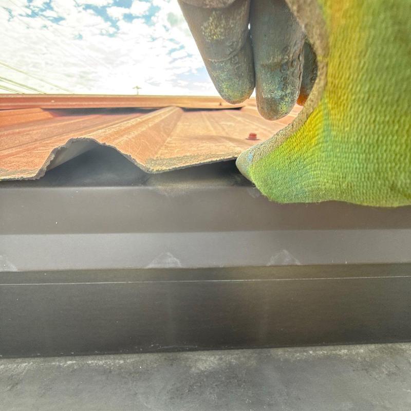 Metal roof panel lifted near flashing for inspection