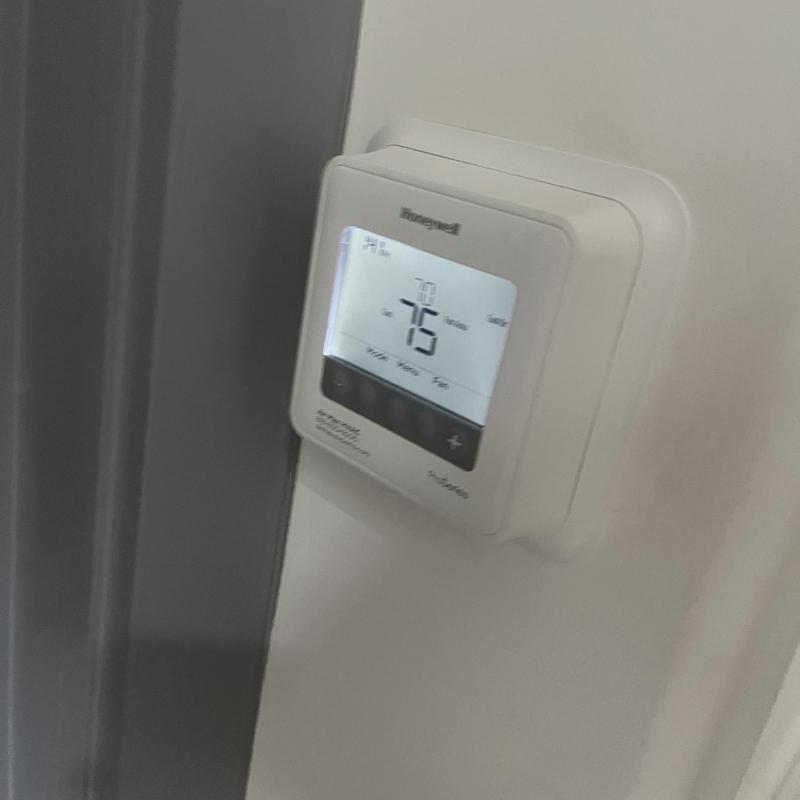 Digital thermostat display set to 75 degrees on wall