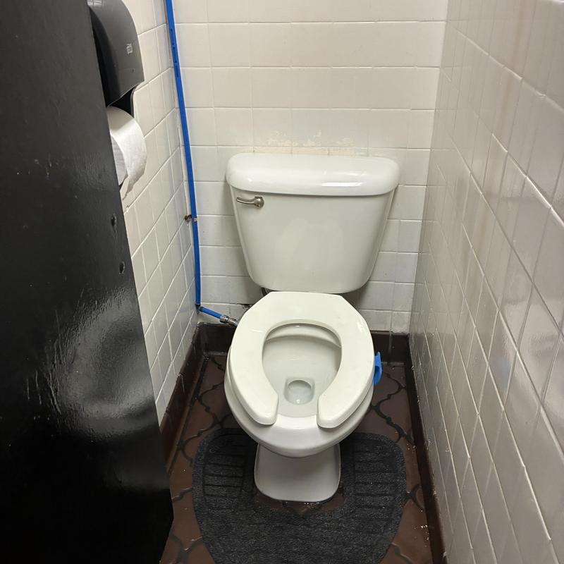 Commercial toilet with open seat in small restroom stall