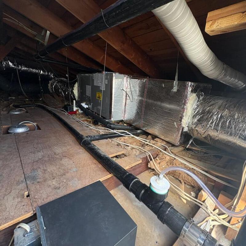 Heat pump system ductwork and condensate drain line in attic