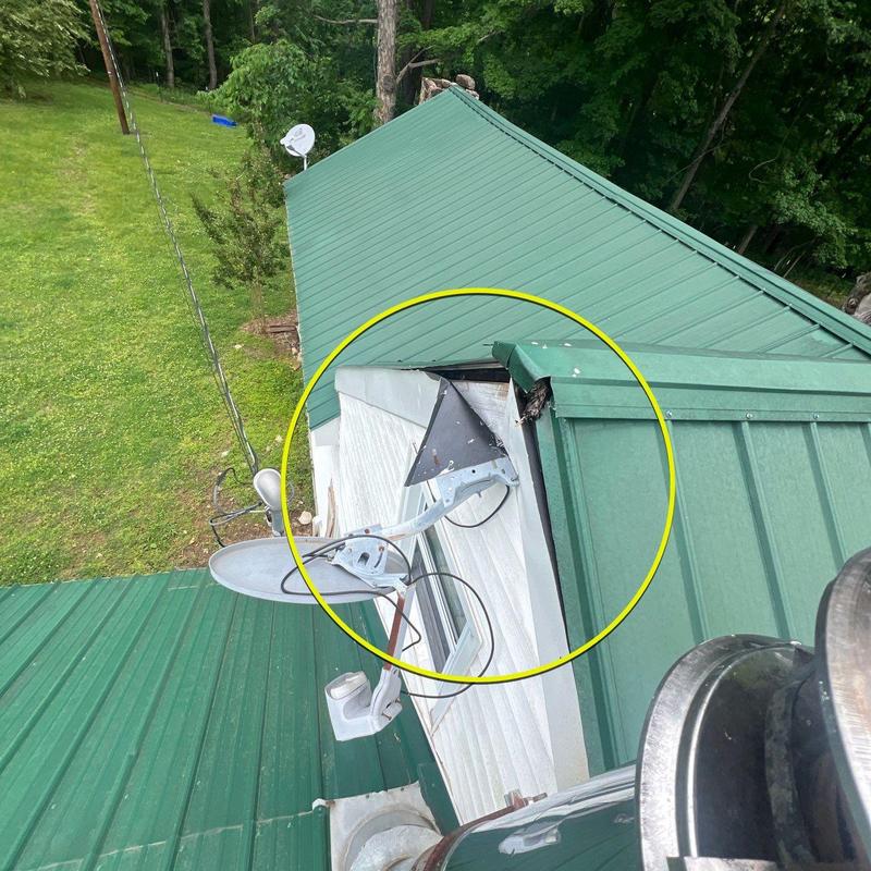 Metal roof valley with storm damage near satellite dish