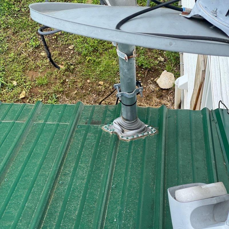 Satellite dish mount on green metal roof panel