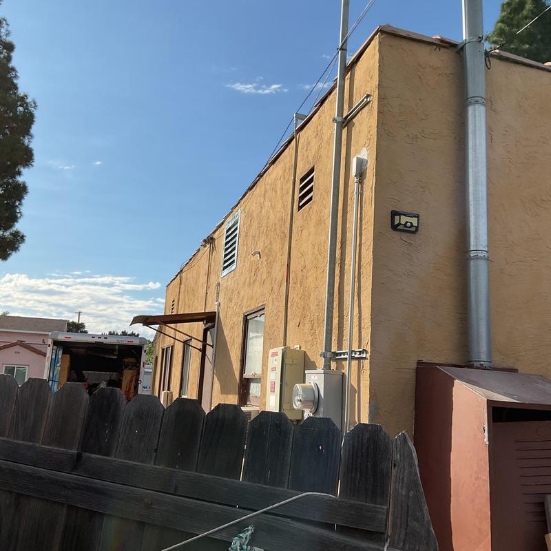 Heat pump with electrical panel and vent pipes on building exterior