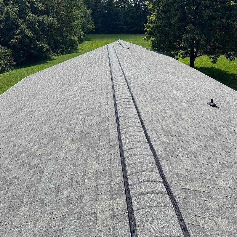 Asphalt shingle roof with ridge vent in green yard