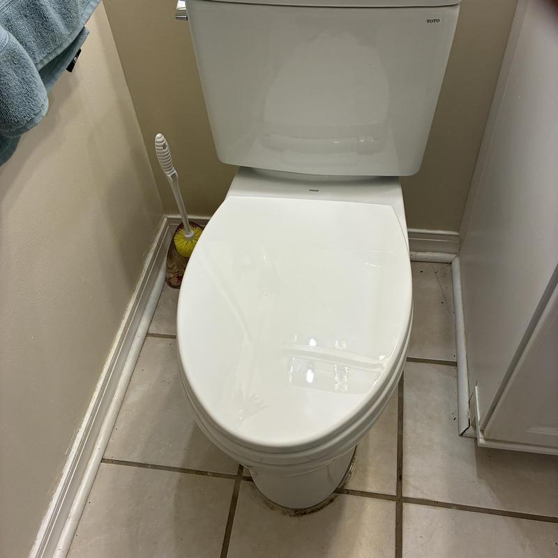 Toilet installation in bathroom corner with cleaning brush