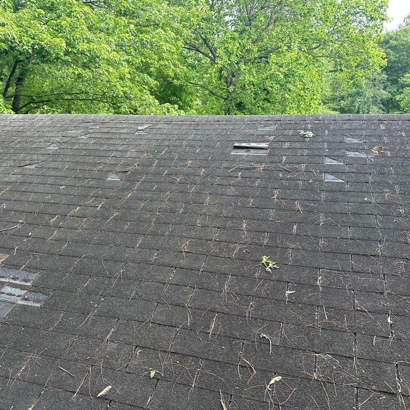 Asphalt shingle roof with hailstorm damage and debris