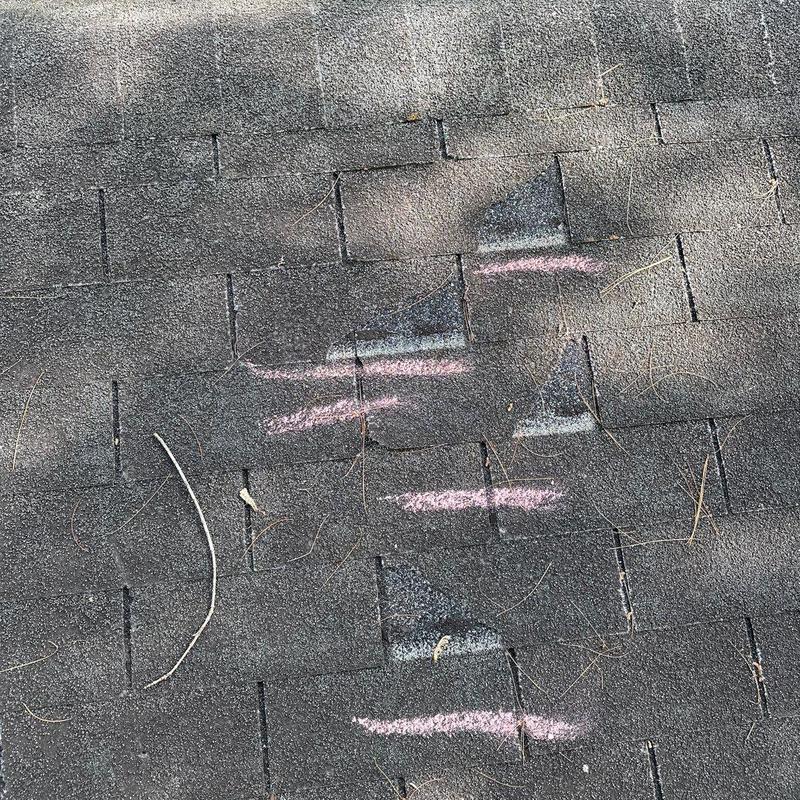 Asphalt roof shingles with hail damage marked in chalk