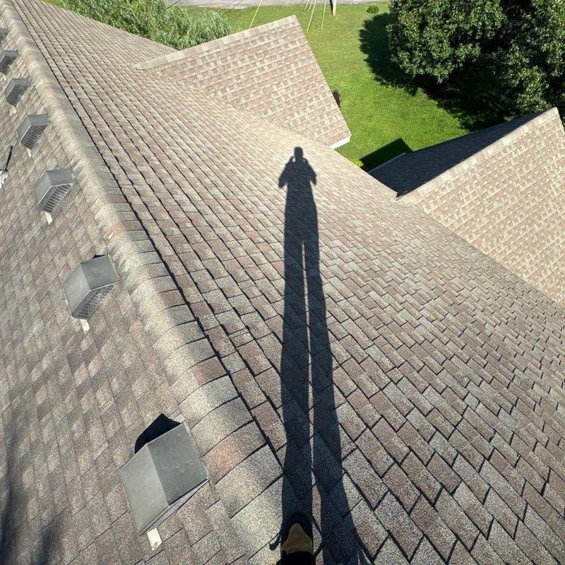 Asphalt shingle roofing with ridge vent inspection in sunlight