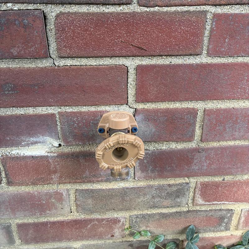 Outdoor hose faucet installed on brick wall