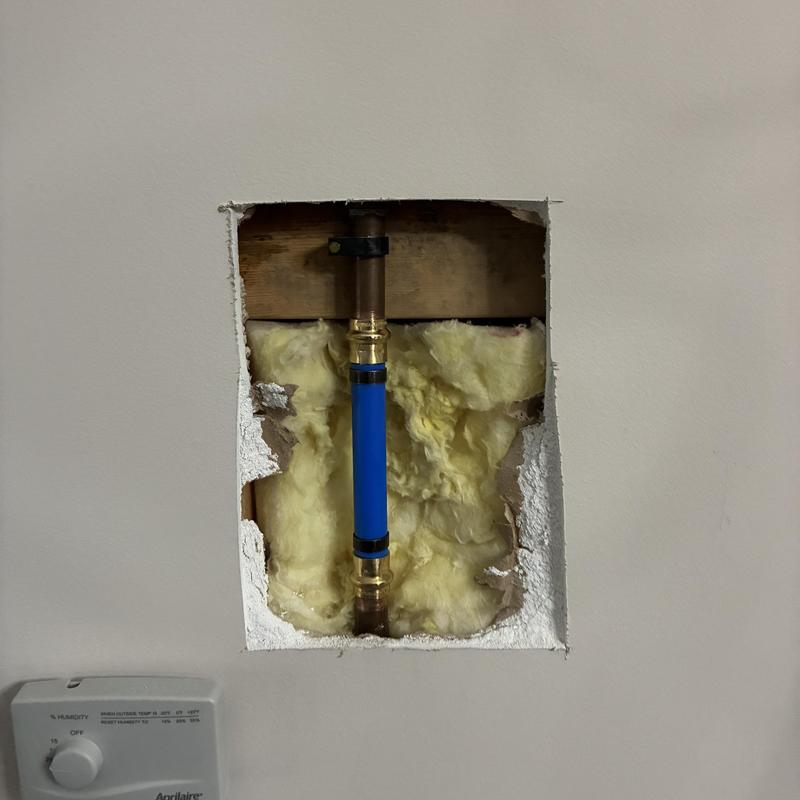 Copper water pipe with blue repair sleeve in wall cavity