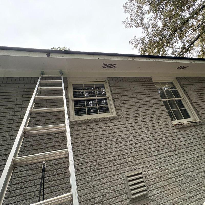 White gutters with ladder on brick house exterior