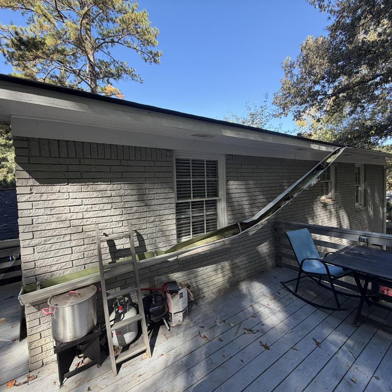 White gutter section detached from house exterior wall