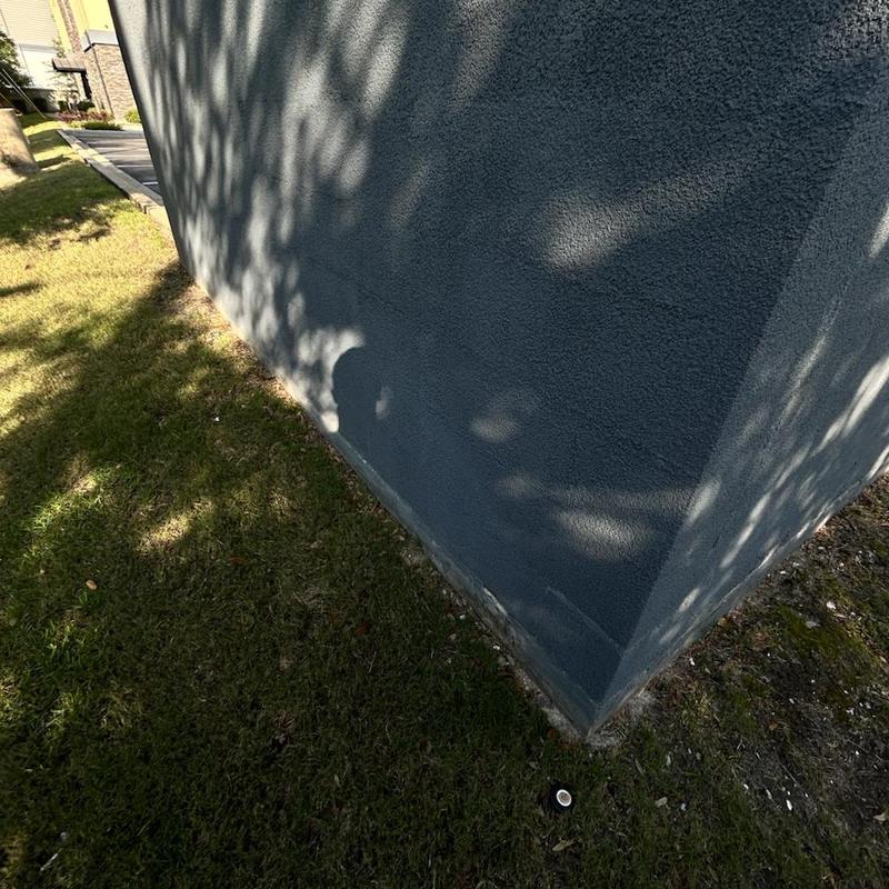 Building exterior foundation with grass and shadowed wall
