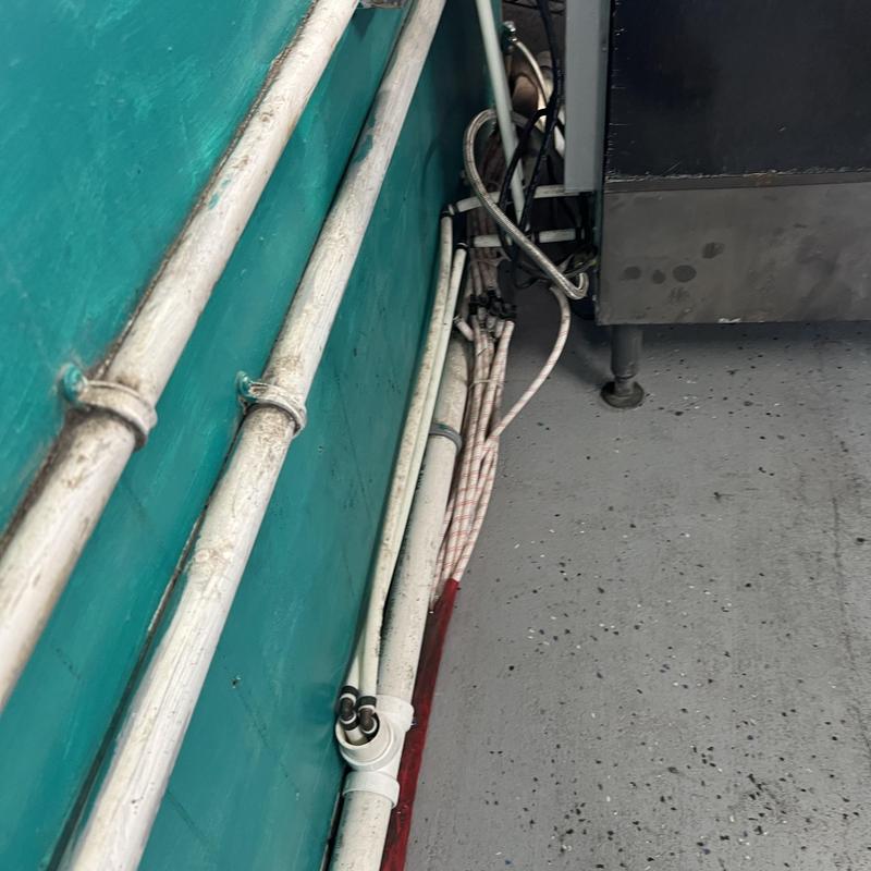 Commercial sink drain and supply piping along wall