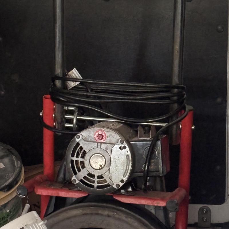 Drain auger machine motor with cable coil on red frame