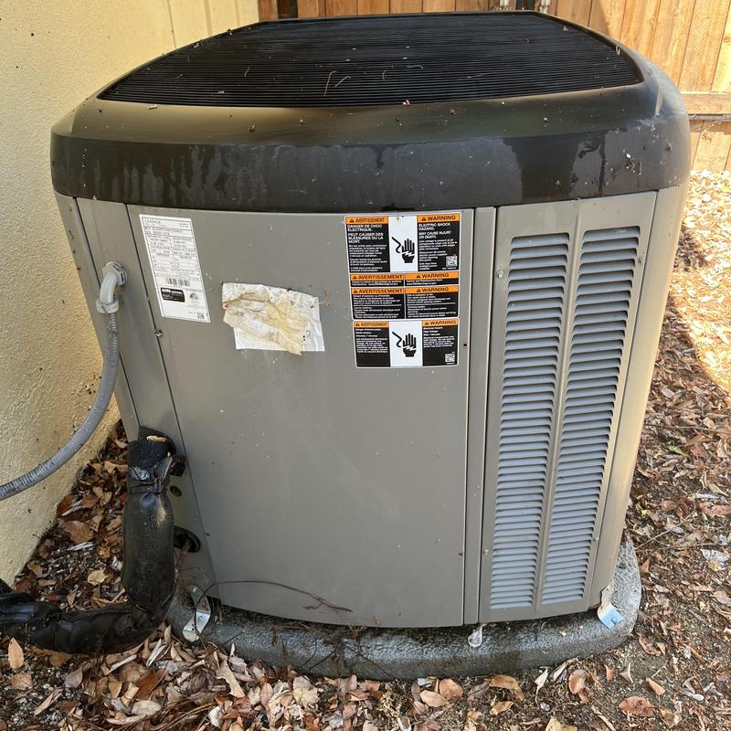 Air conditioning condenser unit outdoors with warning labels
