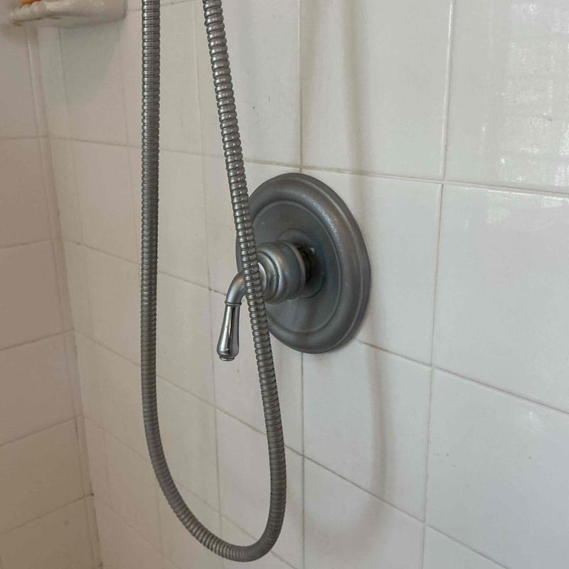 Single handle shower valve and hose on tiled wall