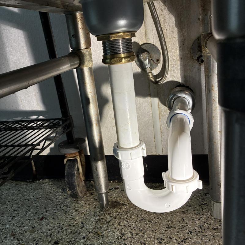 Commercial kitchen sink drain trap and pipes under sink