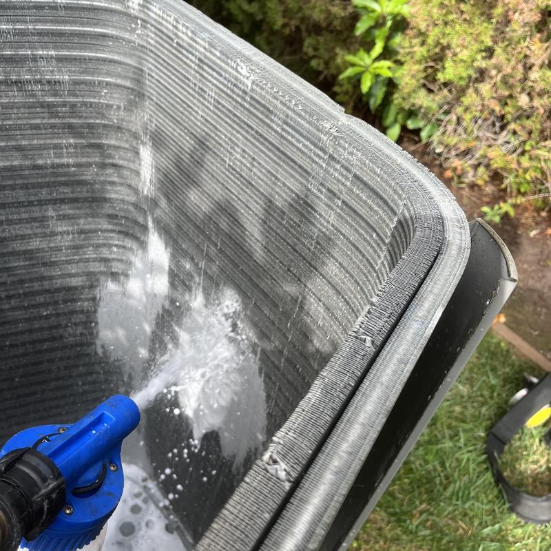 Condenser coil being cleaned with water spray outdoors