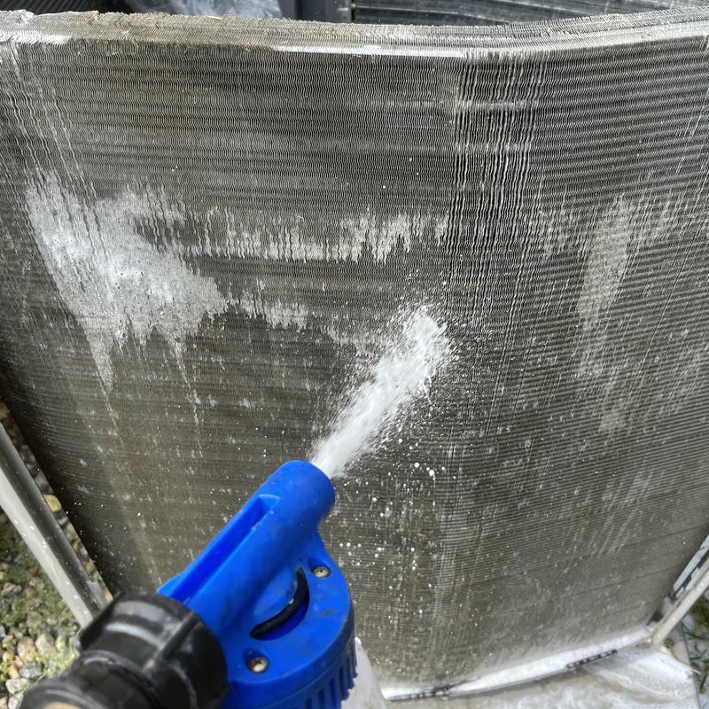 Condenser coil spraying cleaning water on fins