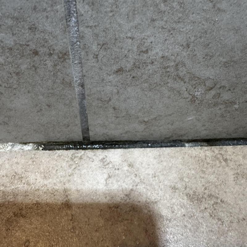 Shower drain pan with visible water leakage and damage