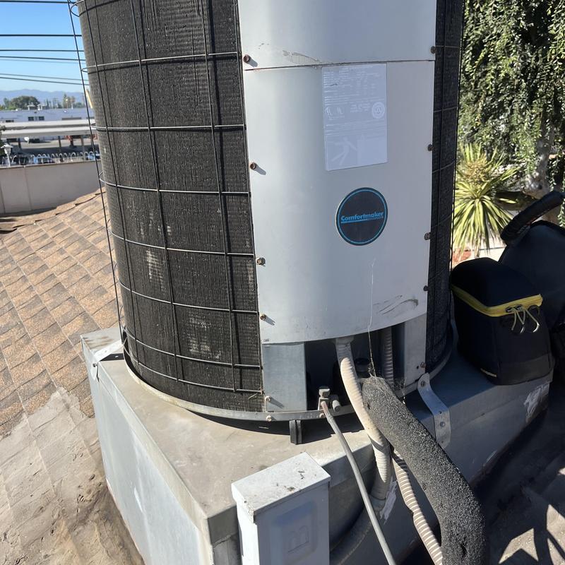 Air conditioner condenser unit on rooftop with tools nearby