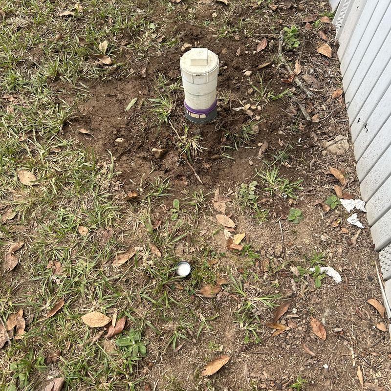 Mainline cleanout pipe exposed in grassy yard near building