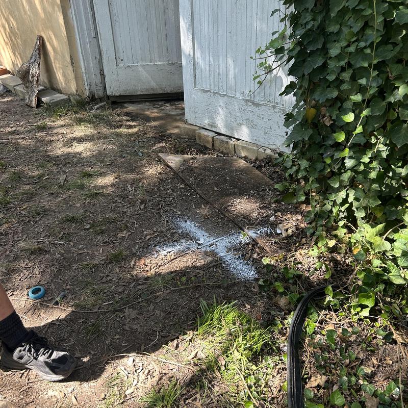 Drain pipe blockage marked with white paint outdoors near door