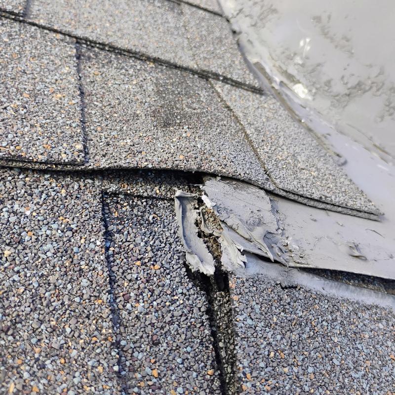 Asphalt shingle roof damage near flashing sealant