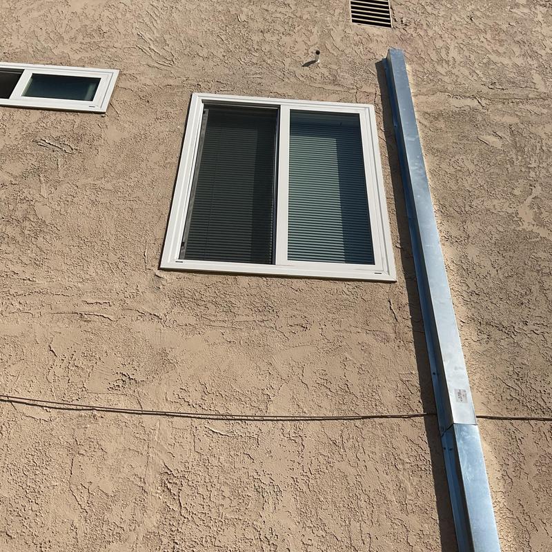 Metal HVAC vent duct on exterior stucco wall