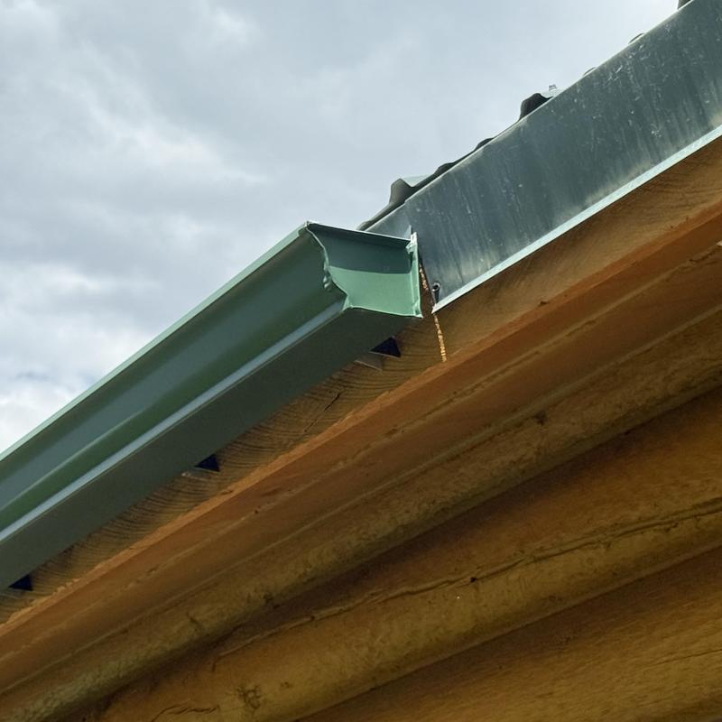 Gutter installation on rustic wooden home roof edge Gutter installation on rustic wooden home roof edge
