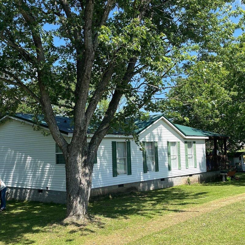 Metal roof on white house surrounded by trees