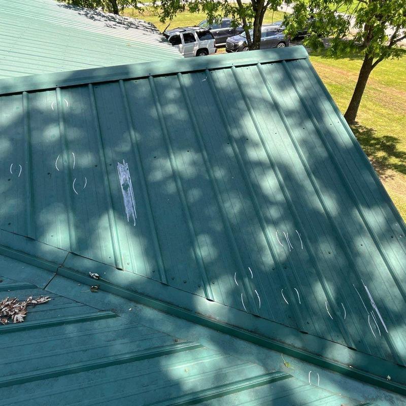 Metal roof with marked storm damage spots