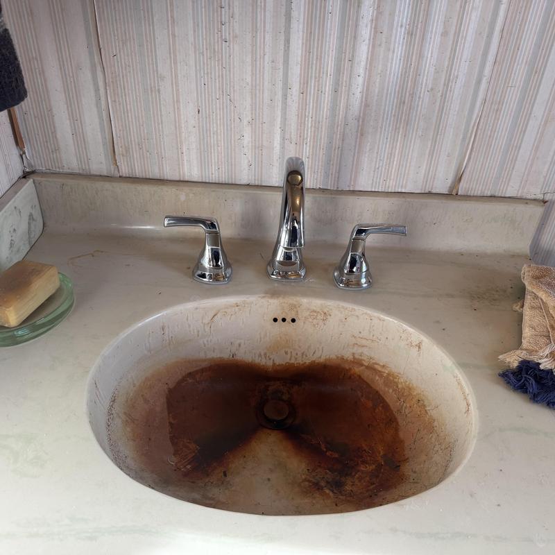 Bathroom sink with heavy iron staining and new faucet installed