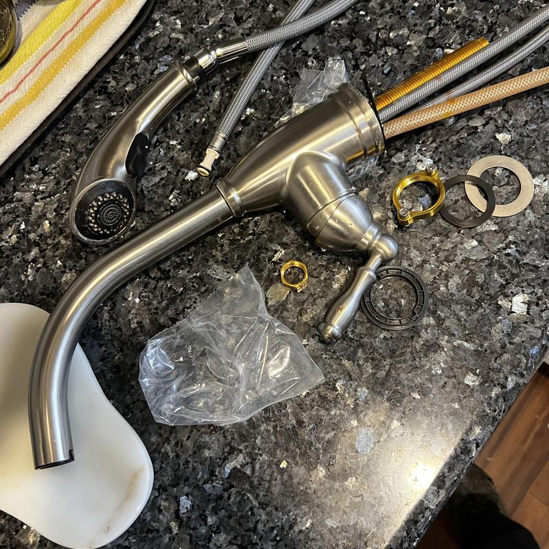 Kitchen faucet and sprayer with installation parts on counter