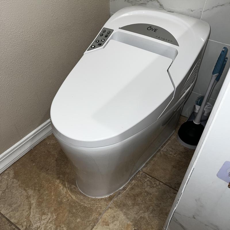 Smart toilet with control panel in bathroom corner