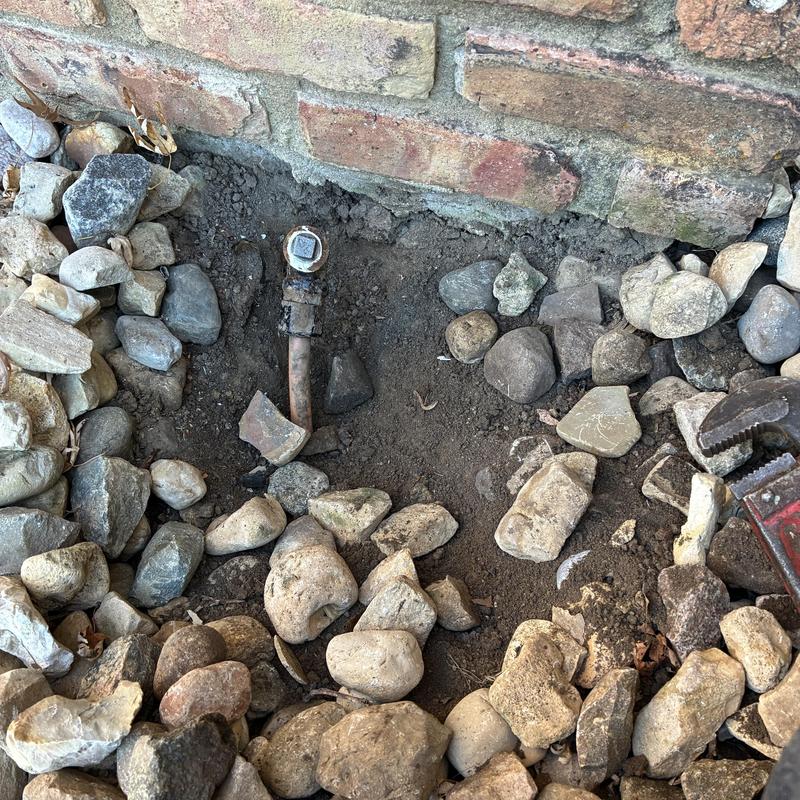 Gas line capped outside brick fireplace with surrounding rocks
