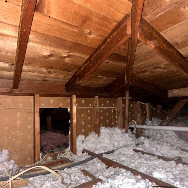 Attic insulation with exposed wooden beams and wiring