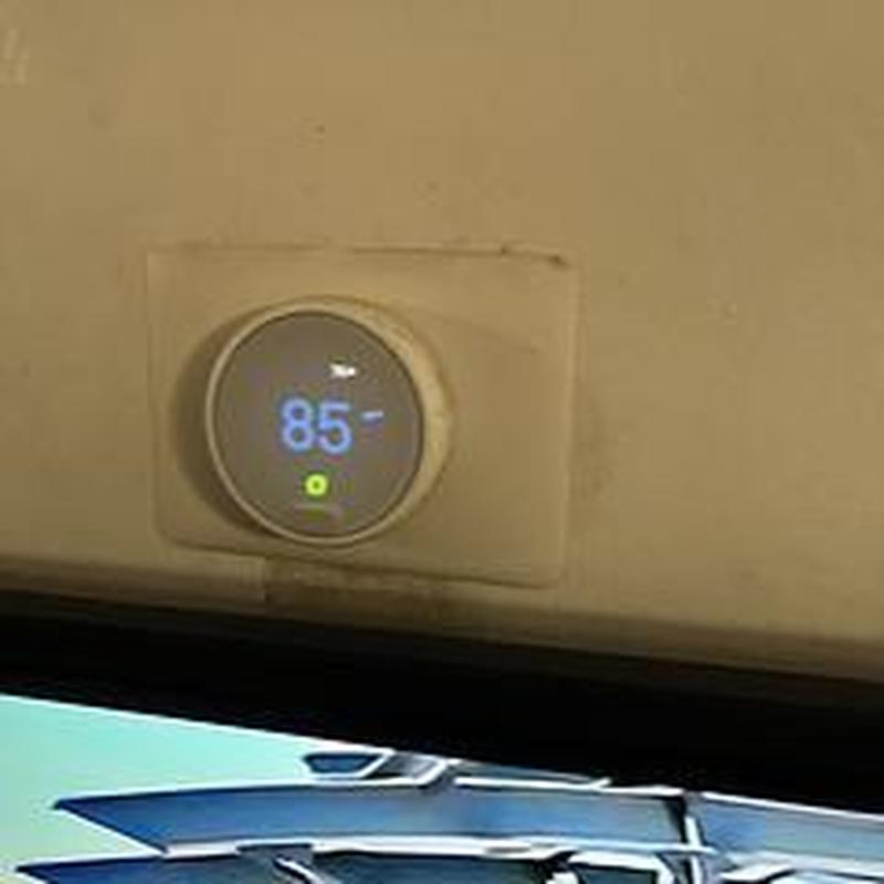 Smart thermostat set to 85 degrees on beige wall