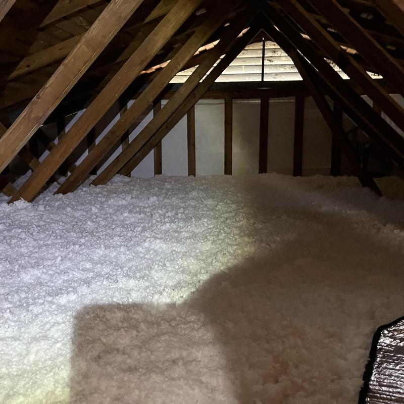 Attic insulation layer covering wooden joists and rafters