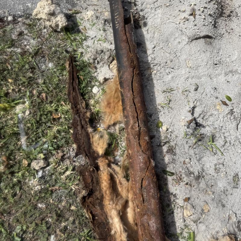Corroded metal water pipe removed outdoors