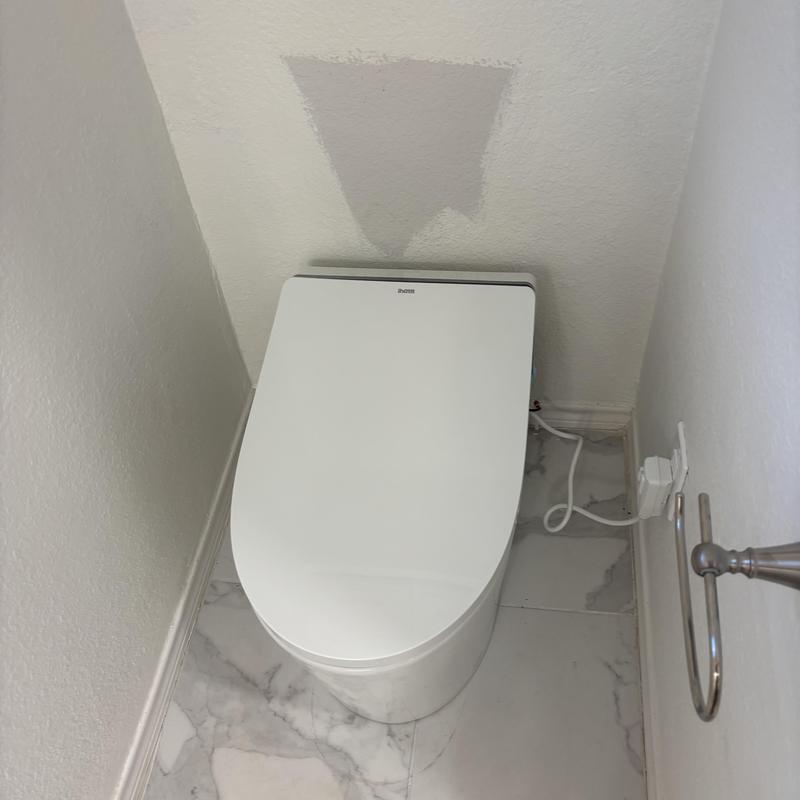 Toilet with electronic bidet seat in bathroom corner