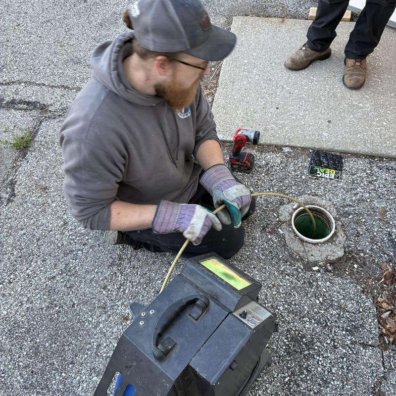Main sewer line with snake machine in use outdoors