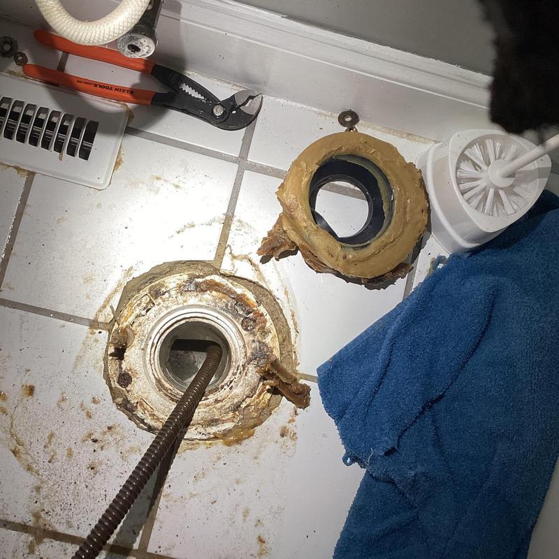 Toilet flange with wax ring removed on tile floor