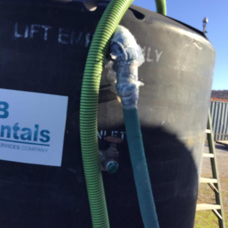 Holding tank with connected green hoses outdoors